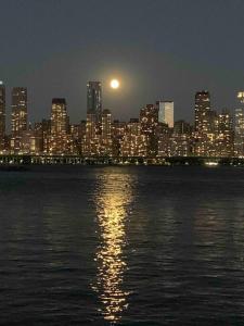 a city skyline at night with the moon over the water at Manhattan skyline under your feet in North Bergen