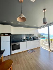a kitchen with white cabinets and a view of the ocean at Casa do mar in São Vicente