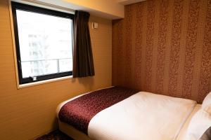 a small bedroom with a bed and a window at Hotel. Links Namba in Osaka
