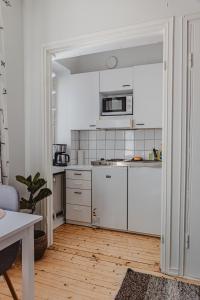 eine Küche mit weißen Schränken und einer Mikrowelle in der Unterkunft Nordstay - Trendy Studio by the North Harbor self check-in in Helsinki