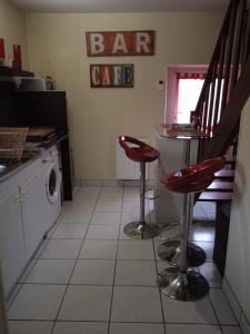 een keuken met een bar en twee rode krukken bij Chez Fa et Pascal in Lanester