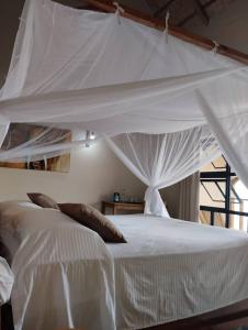1 dormitorio con 1 cama blanca con dosel en Joma Adventure Lodge, en Senga