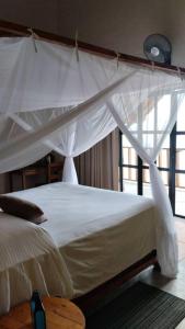 Joma Adventure Lodge في Senga: غرفة نوم بسرير أبيض مع مظلة