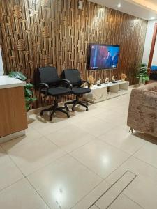 uma sala de espera com três cadeiras e uma televisão em Luxury rooms studioLahore em Lahore