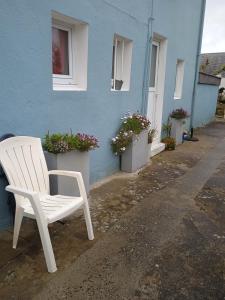 une chaise blanche assise à l'extérieur d'un bâtiment bleu dans l'établissement Chez Fa et Pascal, à Lanester