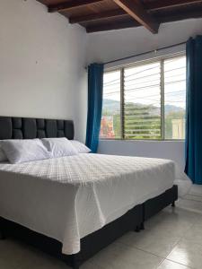 a bed in a bedroom with a large window at Hotel Mallorca Estadio, Medellin in Medellín