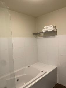a white bathroom with a tub and a shelf with towels at Herberg de Wildeman in Lemmer