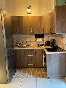 a kitchen with wooden cabinets and a sink and a stove at Lux Apartment 10m From Center in Alexandroupoli