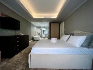 une chambre avec un grand lit blanc et une salle de bain dans l'établissement CLB Sea view Apartment, à Constanţa