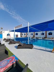 a large swimming pool with a blue canopy next to a building at Sharjah International Airport Hotel in Sharjah