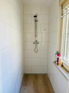 La salle de bains carrelée de blanc est pourvue d'une douche et d'une fenêtre. dans l'établissement Gemütliche Unterkunft in Baden-Baden direkt am Schwarzwald, à Baden-Baden