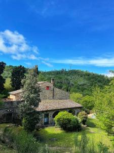 an old stone house with a hill in the background at Casa nel bosco Il Grottone in Montaione