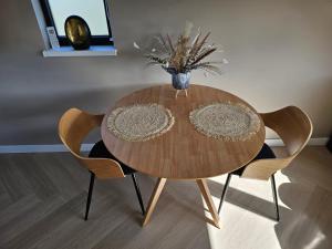 una mesa de madera con 2 sillas y un jarrón de flores en Ybizee, en Yerseke