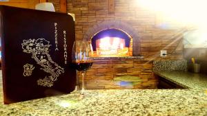 a glass of wine sitting next to a brick oven at Pension Central in Saas-Almagell
