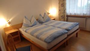 a bed with blue and white sheets and pillows at Pension Central in Saas-Almagell