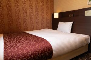 a hotel room with a bed with white sheets at Hotel. Links Namba in Osaka