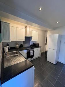 eine Küche mit einer Spüle und einem weißen Kühlschrank in der Unterkunft Beautiful Home near Birmingham in Smethwick