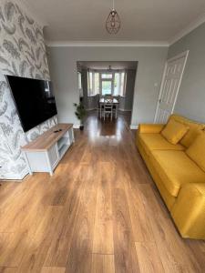 sala de estar con sofá amarillo y mesa en Beautiful Home near Birmingham, en Smethwick