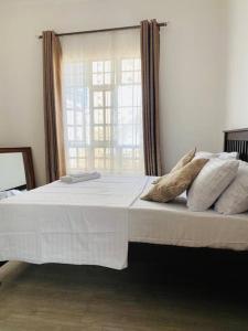 sypialnia z białym łóżkiem z poduszkami i oknem w obiekcie Serenity Homes Arusha w mieście Arusza