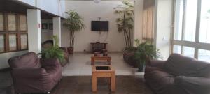 a living room with couches and a tv and plants at Hotel La Rocca, Goiânia in Goiânia
