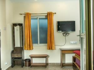 Habitación con TV y cortinas naranjas. en Close 2 Heaven, en Kodaikanal