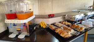 a kitchen with a counter with a bunch of food at Hotel La Rocca, Goiânia in Goiânia