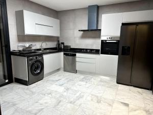 cocina con armarios blancos, lavadora y secadora en Appartement haut standing 3 min du parc prestigia, en Fez