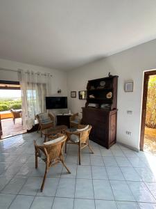 Una sala de estar con un sofá y sillas y un televisor. en Villa Chiccolina, en Stintino