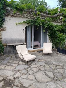 2 sillas blancas sentadas en un patio de piedra en B&B Chambre indépendante double, en Deaux