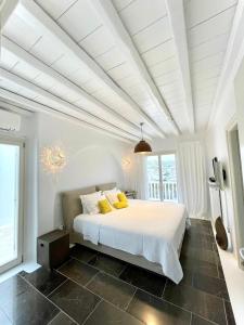 a bedroom with a large white bed with yellow pillows at Grace Villa Mykonos in Mýkonos City