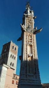 una torre alta con una estatua delante de un edificio en Casa Rural El Encuentro, en Villalón de Campos