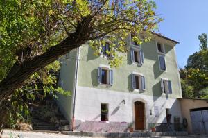 a green and white building with a tree at Camping White Rock in Castellane