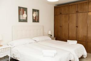 1 dormitorio con 1 cama blanca grande y armarios de madera en Piso Muralla Romana, en León