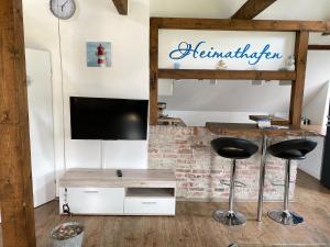 un salon avec une télévision et deux tabourets dans l'établissement Freistehendes Friesenhaus Heimathafen, à Halbemond