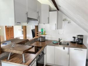 une cuisine avec des armoires blanches et un comptoir en bois dans l'établissement Freistehendes Friesenhaus Heimathafen, à Halbemond