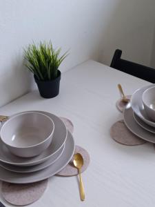 una mesa con platos y cucharas y una planta en ella en Charmant studio avec parking fermé proximité autoroute en Mulhouse