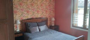 Schlafzimmer mit einem Bett mit Blumentapete in der Unterkunft Gite La Bicyclette in Godewaersvelde