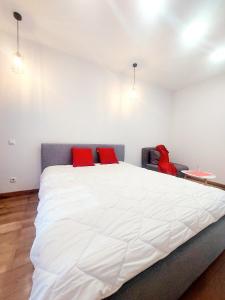 ein Schlafzimmer mit einem großen weißen Bett mit roten Kissen in der Unterkunft Новобудова ЗЕЛЕНА 261 Пасічна Сихівська in Lwiw
