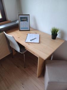 un escritorio de madera con reloj y una planta en Charmant studio avec parking fermé proximité autoroute en Mulhouse