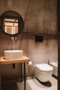 La salle de bains est pourvue de toilettes blanches et d'un miroir. dans l'établissement Comàr suite, à Monopoli