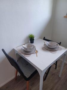 una mesa blanca con platos y utensilios. en Charmant studio avec parking fermé proximité autoroute en Mulhouse