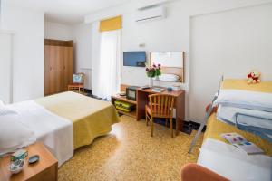 Habitación de hotel con 2 camas y escritorio en Hotel Mayola, en San Bartolomeo al Mare