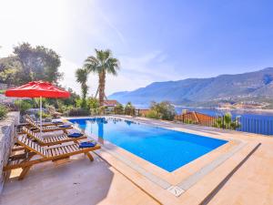 a swimming pool with lounge chairs and an umbrella at Villa Sarpedon in Kaş