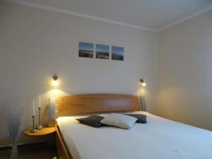 a bedroom with a large white bed with two lamps at Ferienwohnung 2 in Pudagla auf der Insel Usedom in Pudagla +5 photos