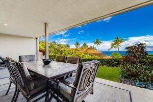 a table and chairs on a patio with a view of the ocean at MAKENA SURF #C102 condo in Wailea