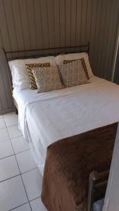 un letto con lenzuola e cuscini bianchi di Quiet and cozy cunuco guesthouse in Savaneta a Savaneta