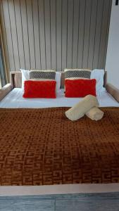 a bed with two red pillows and a blanket at Quiet and cozy cunuco guesthouse in Savaneta in Savaneta