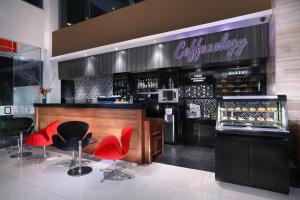 a bar with red chairs and a counter with wine bottles at Hotel Neo Gubeng by ASTON in Surabaya
