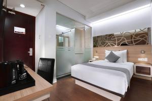 1 dormitorio con cama blanca y TV. en Hotel Neo Gubeng by ASTON, en Surabaya