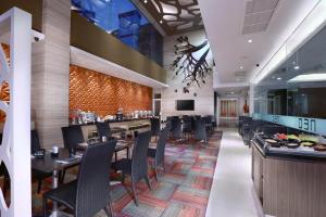 un restaurante con mesas y sillas y un bar en Hotel Neo Gubeng by ASTON, en Surabaya